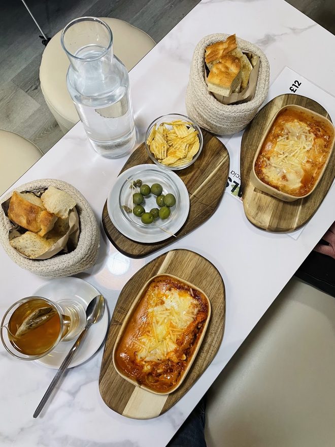 A laid table of baked pasta, bread and dips from above