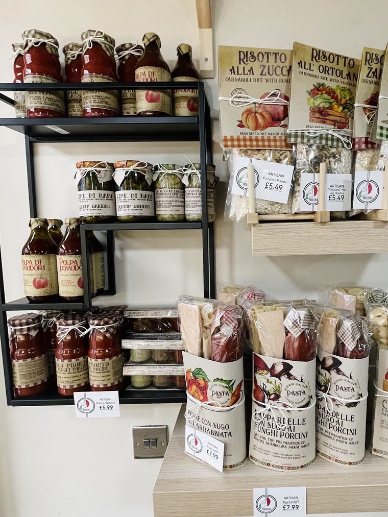 A shelf of Italian pantry goods, passata, pesto and risotto, cropped away from the price tags